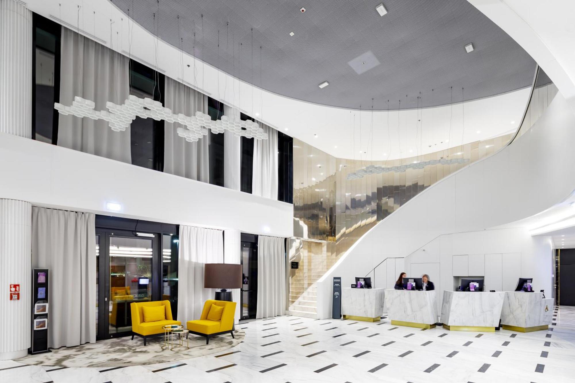 Radisson Blu Resort Swinoujscie Ngoại thất bức ảnh The photo shows a modern interior space, likely a hotel or a lobby area. It features a spacious, open design with high ceilings and a stylish staircase that leads to an upper level. The walls are mostly white, with large windows allowing natural ligh