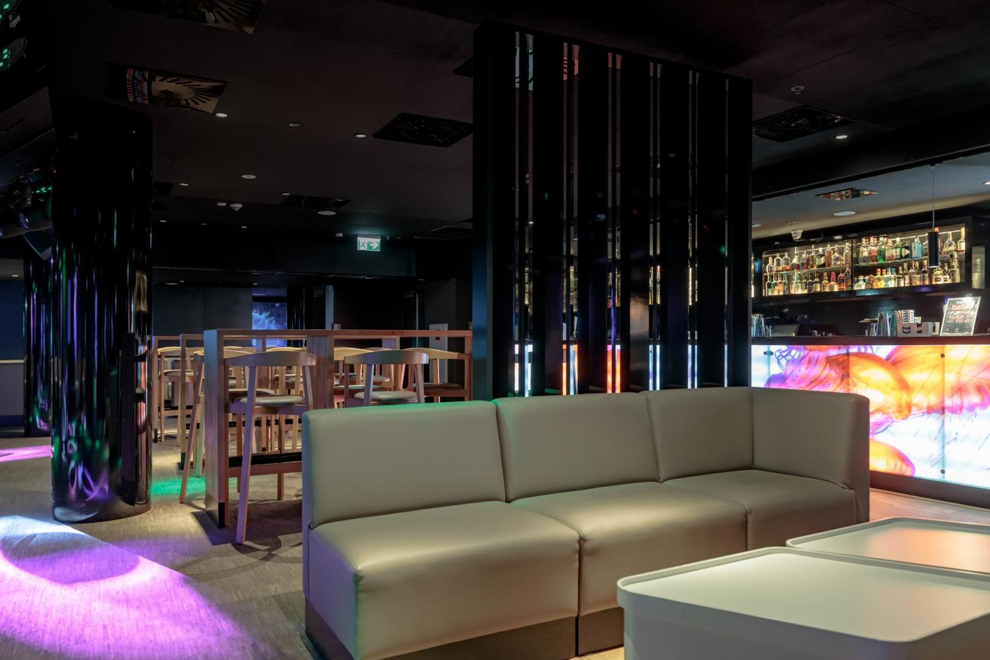 Radisson Blu Resort Swinoujscie Ngoại thất bức ảnh The photo shows the interior of a stylish lounge or bar. The space features a modern design with dark walls and a sleek atmosphere. There is a beige sectional sofa in the foreground, providing a casual seating area. In the background, a bar is visibl