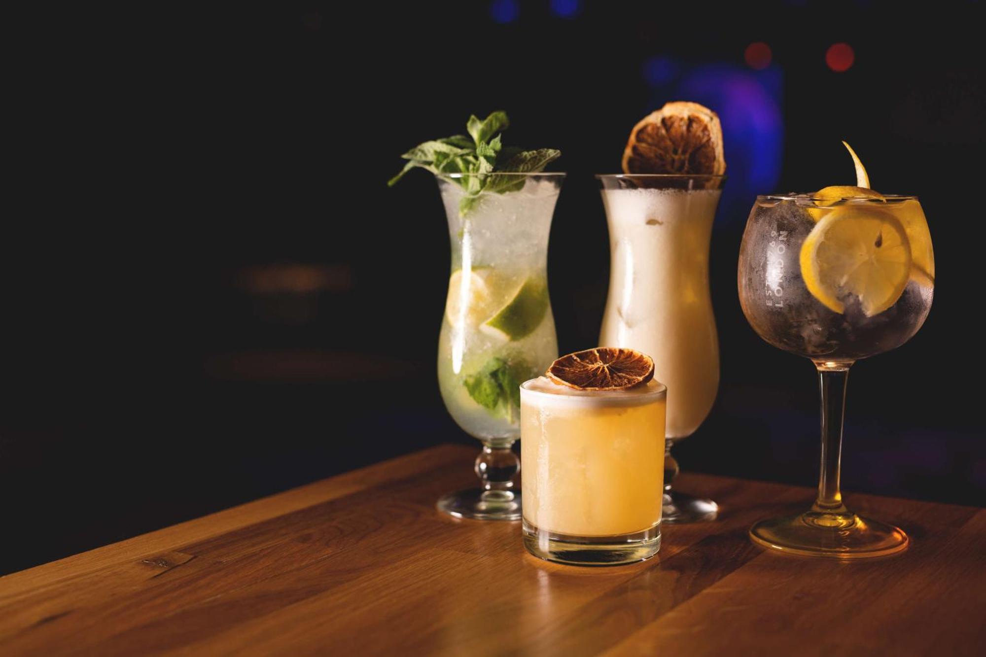 Radisson Blu Resort Swinoujscie Ngoại thất bức ảnh The photo showcases a collection of four different cocktails displayed on a wooden table. 

1. **Mojito**: A tall glass filled with lime slices, mint leaves, and a clear liquid, likely rum-based, garnished with fresh mint.
2. **Creamy Cocktail**: A s