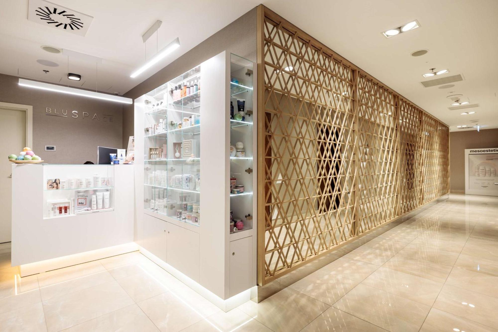 Radisson Blu Resort Swinoujscie Ngoại thất bức ảnh The photo shows a modern interior, likely from a spa or skincare clinic. On the left, there is a reception area with a sleek white counter and an illuminated display showcasing various skincare products. The wall behind the reception features a glass
